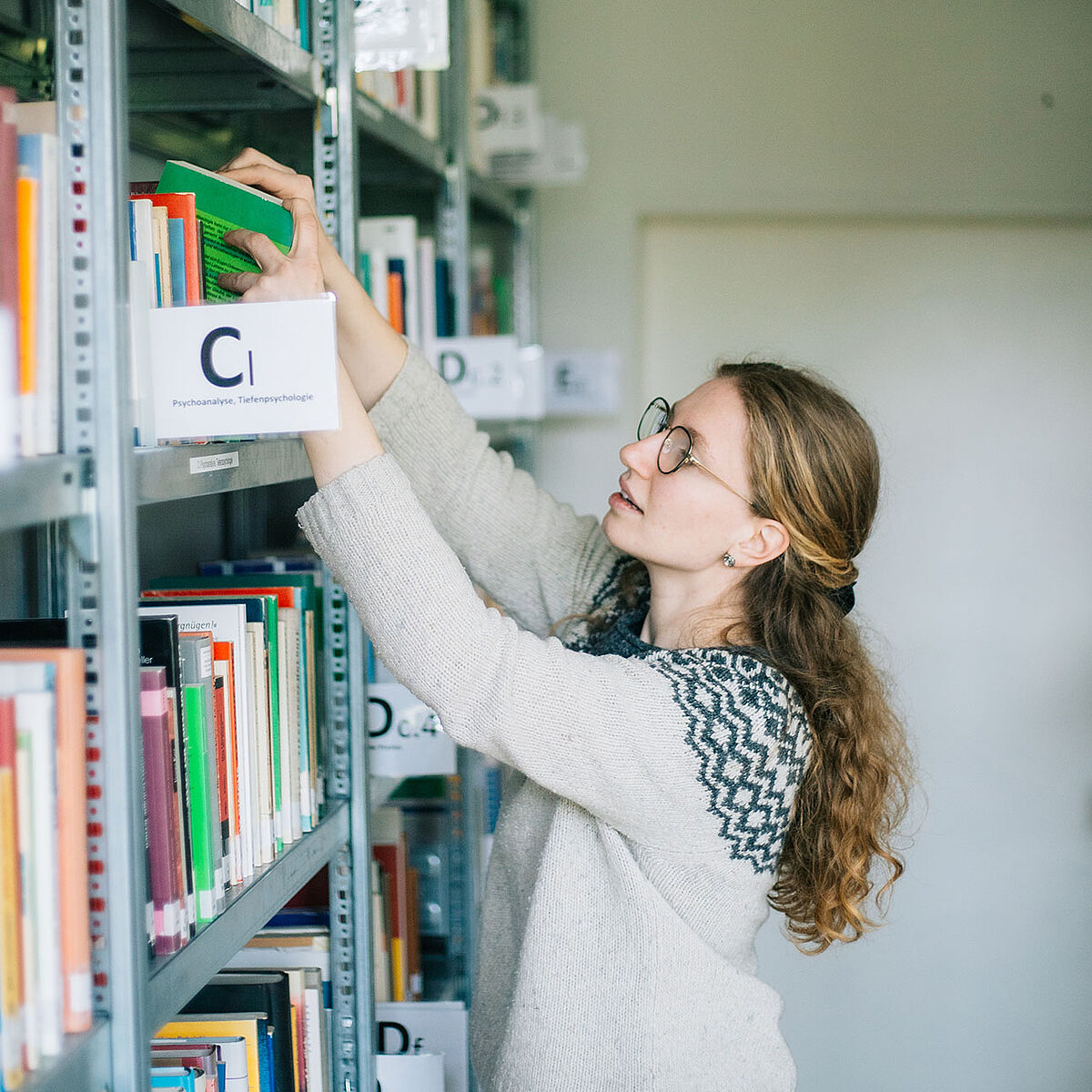 Studentin an einem Bücherregal